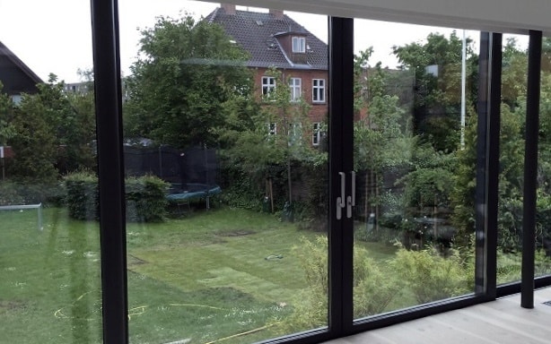 Glasparti med dobbelt skydedør fra NJP A/S. Sorte profiler i aluminium.