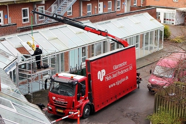Lastbil med kran og sug assisterer ved montering af glasparti. NJP A/S